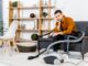 upset man in modern living room sitting on sofa near hoover and looking at camera