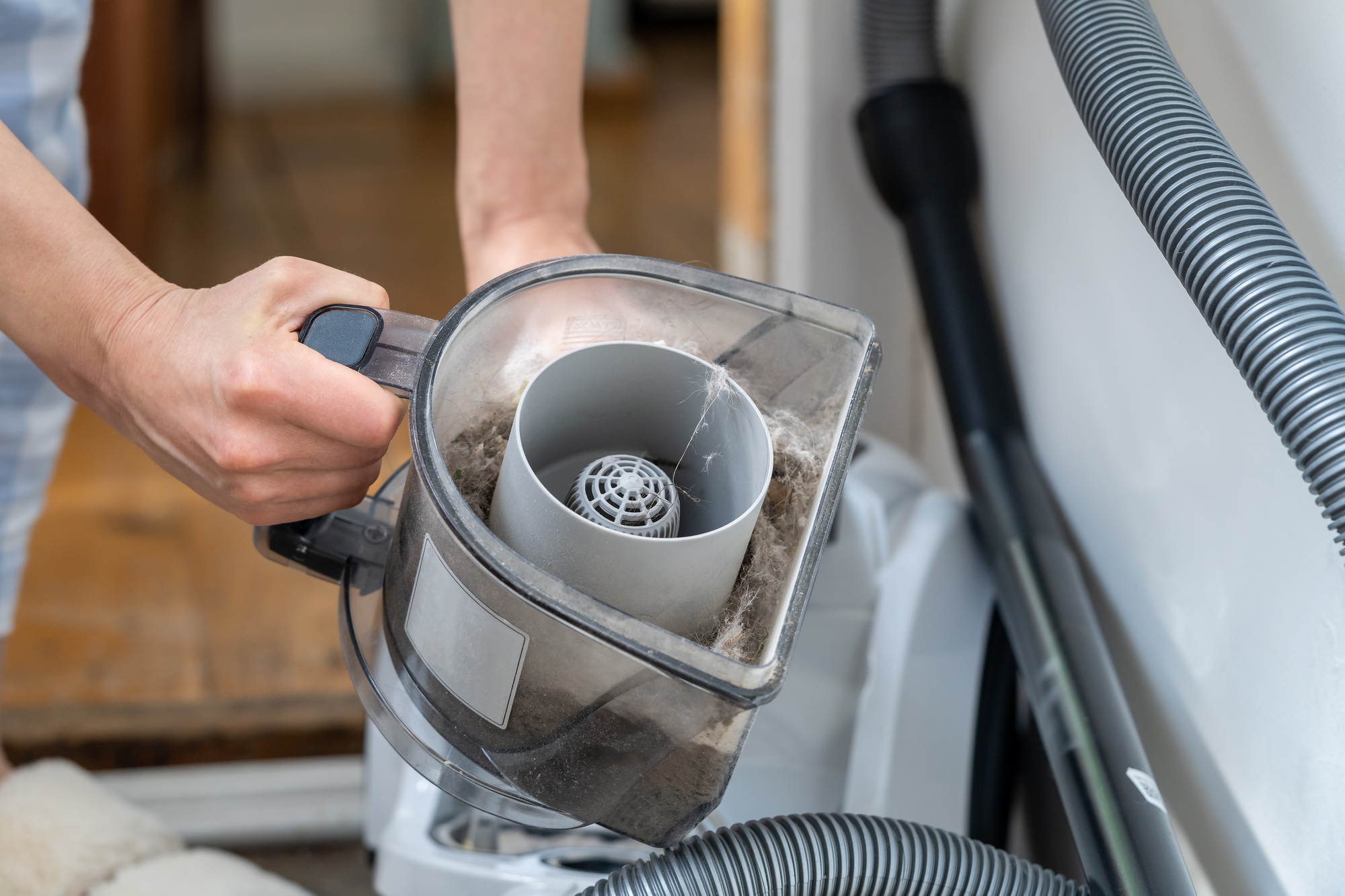Woman opening dust filter out of vacuum cleaner. Housework, household chores