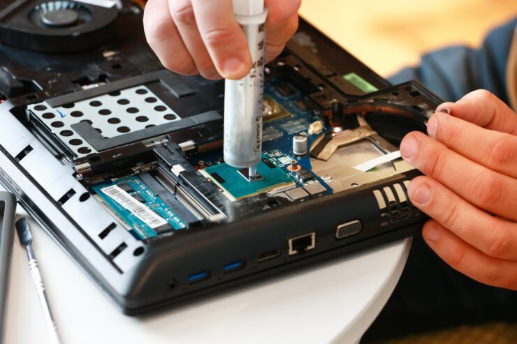 Hand a repairman uses thermal paste syringe apply thermal compound to a CPU. Master replaces thermal