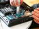 Hand a repairman uses thermal paste syringe apply thermal compound to a CPU. Master replaces thermal