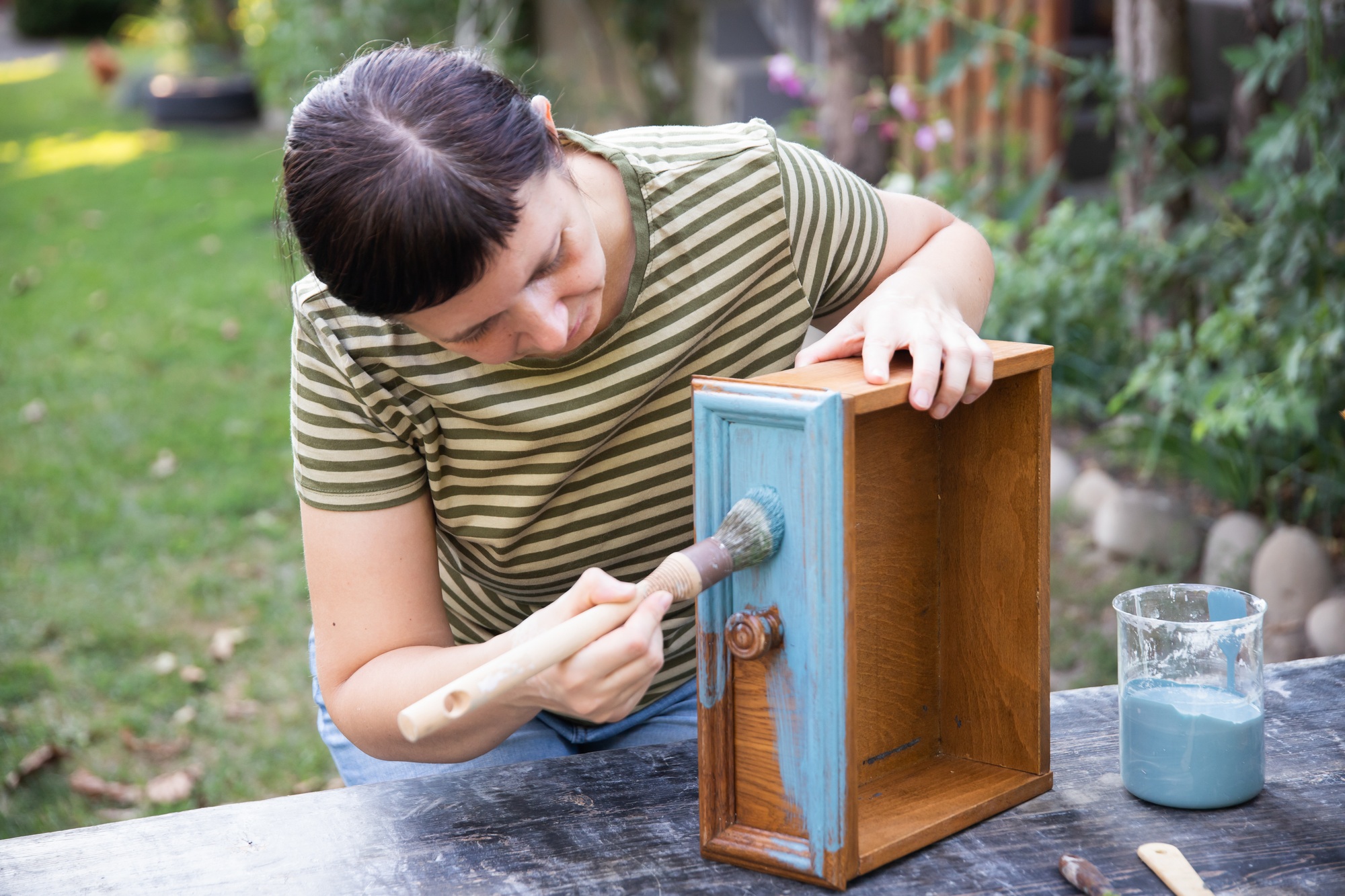 Painting a wooden furniture outdoors, an eco-friendly re-use business.