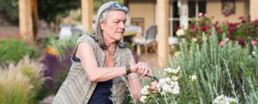 senior grandmother and her 5 year old grandson pruning roses in her garden