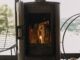 Modern black fireplace with burning fire and firewood on metal stand. Cozy warm moments